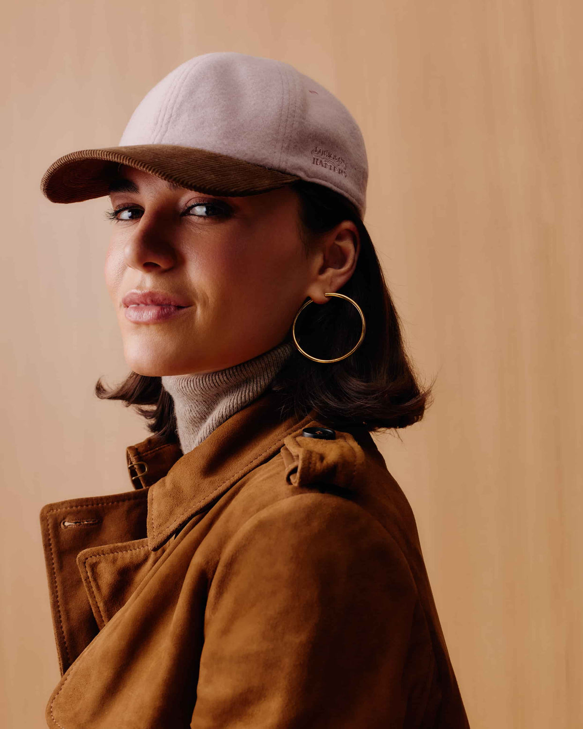 An adjustable baseball cap with a dusty pink cashmere crown and a brown corduroy brim.