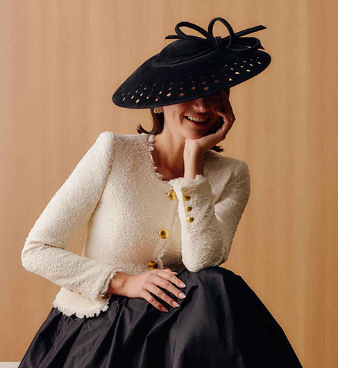 Couture black velour felt saucer hat with punched holes on the brim and a matching bow on top