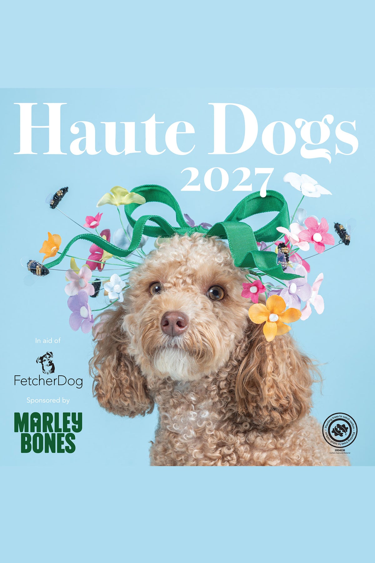 Haute Dogs 2027 calendar cover featuring a fluffy light brown poodle wearing a green ribbon and colorful artificial flowers, with the text 'Haute Dogs 2027' on a light blue background. 