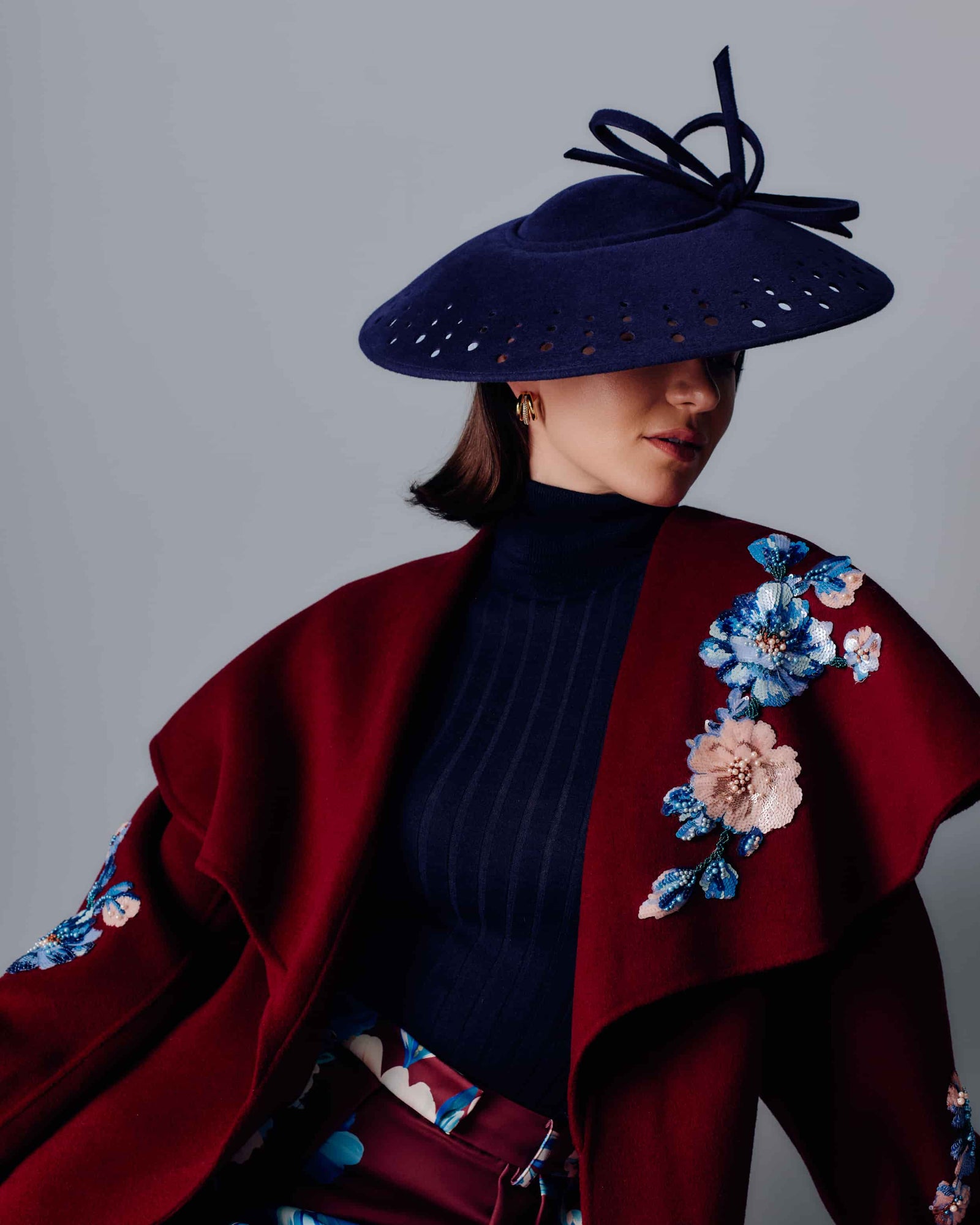 Couture navy velour felt saucer hat with punched holes on the brim and a bow on top