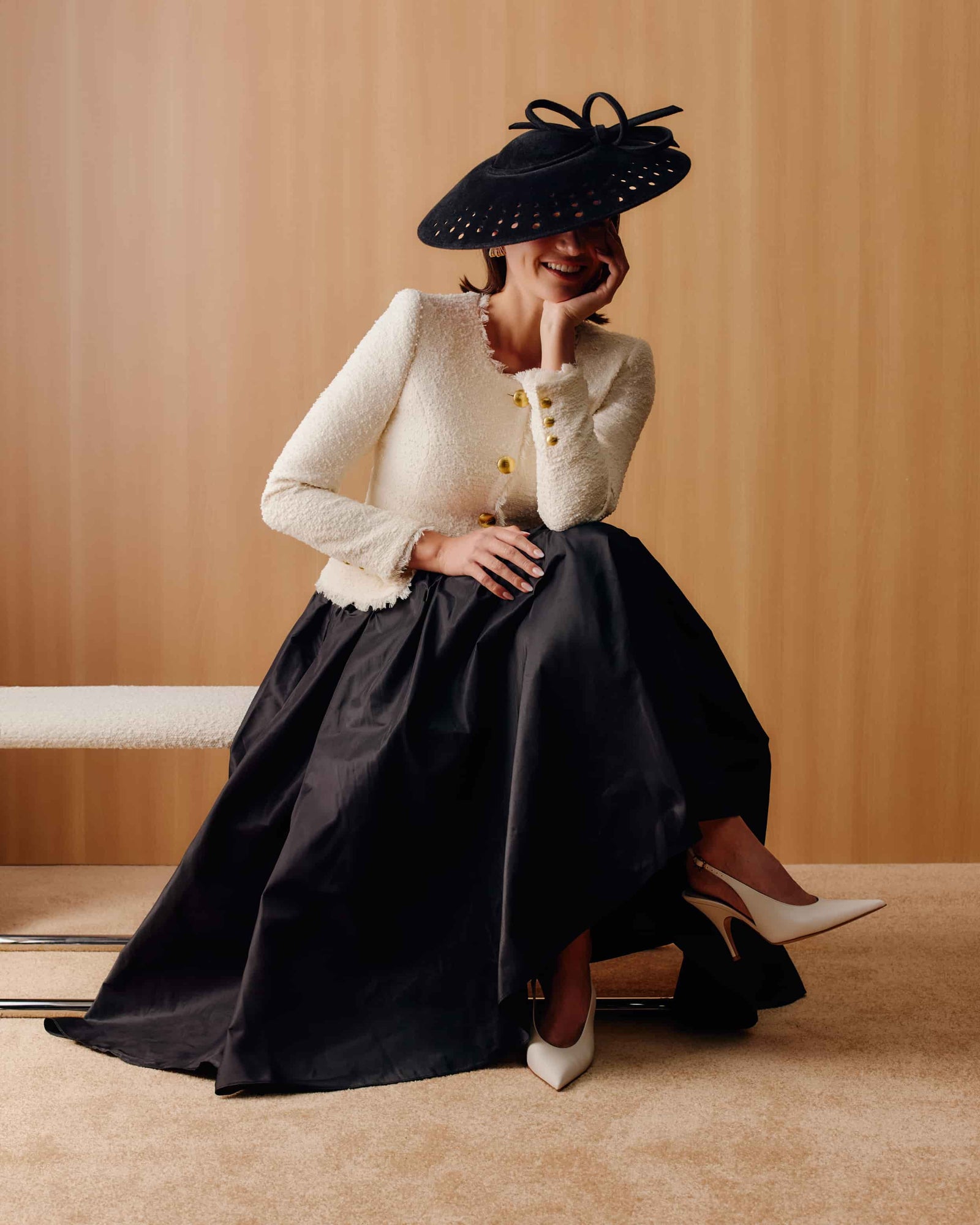 Couture black velour felt saucer hat with punched holes on the brim and a matching bow on top