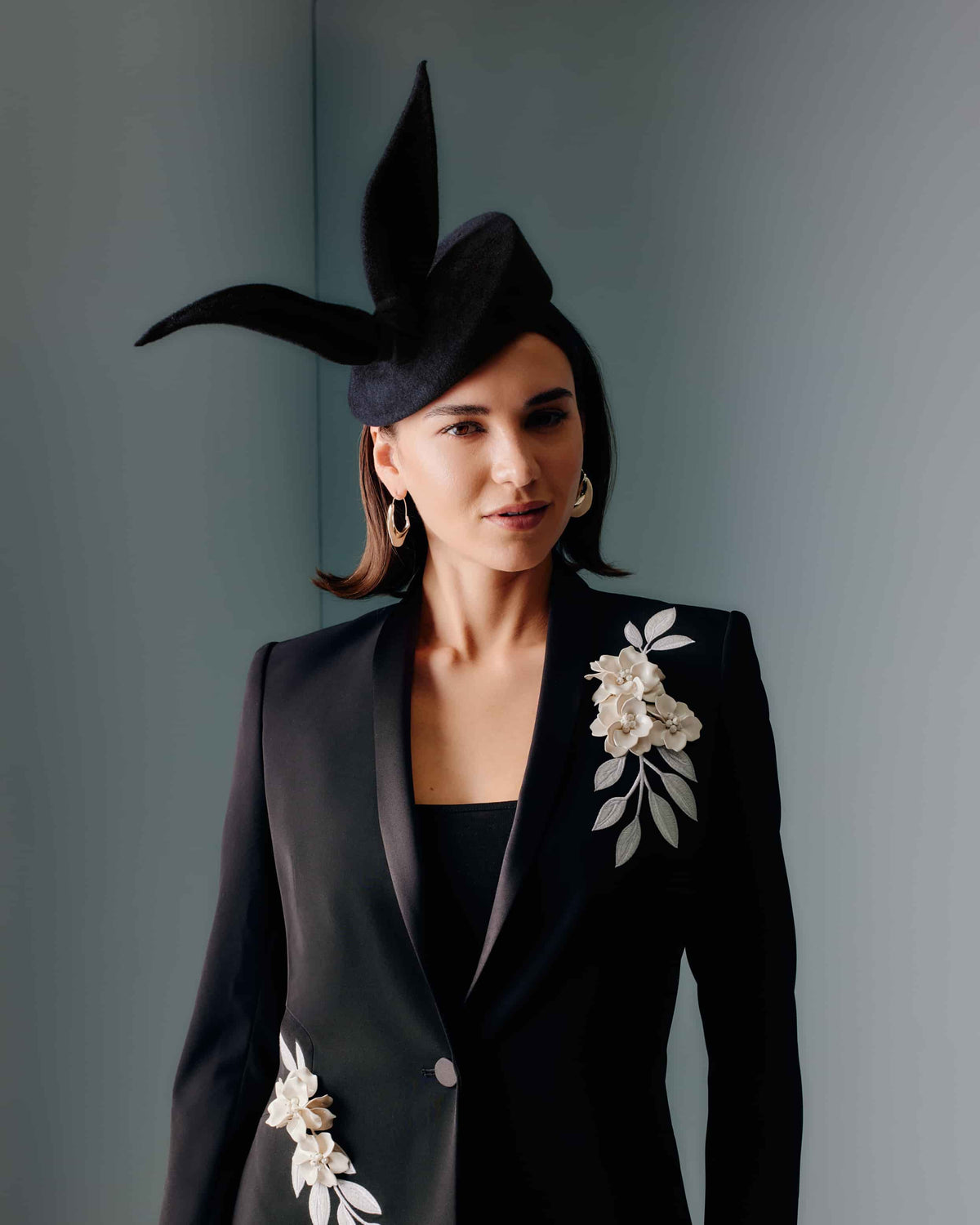 Couture black velour felt percher hat with a rounded base and a sculptural bow at the top.