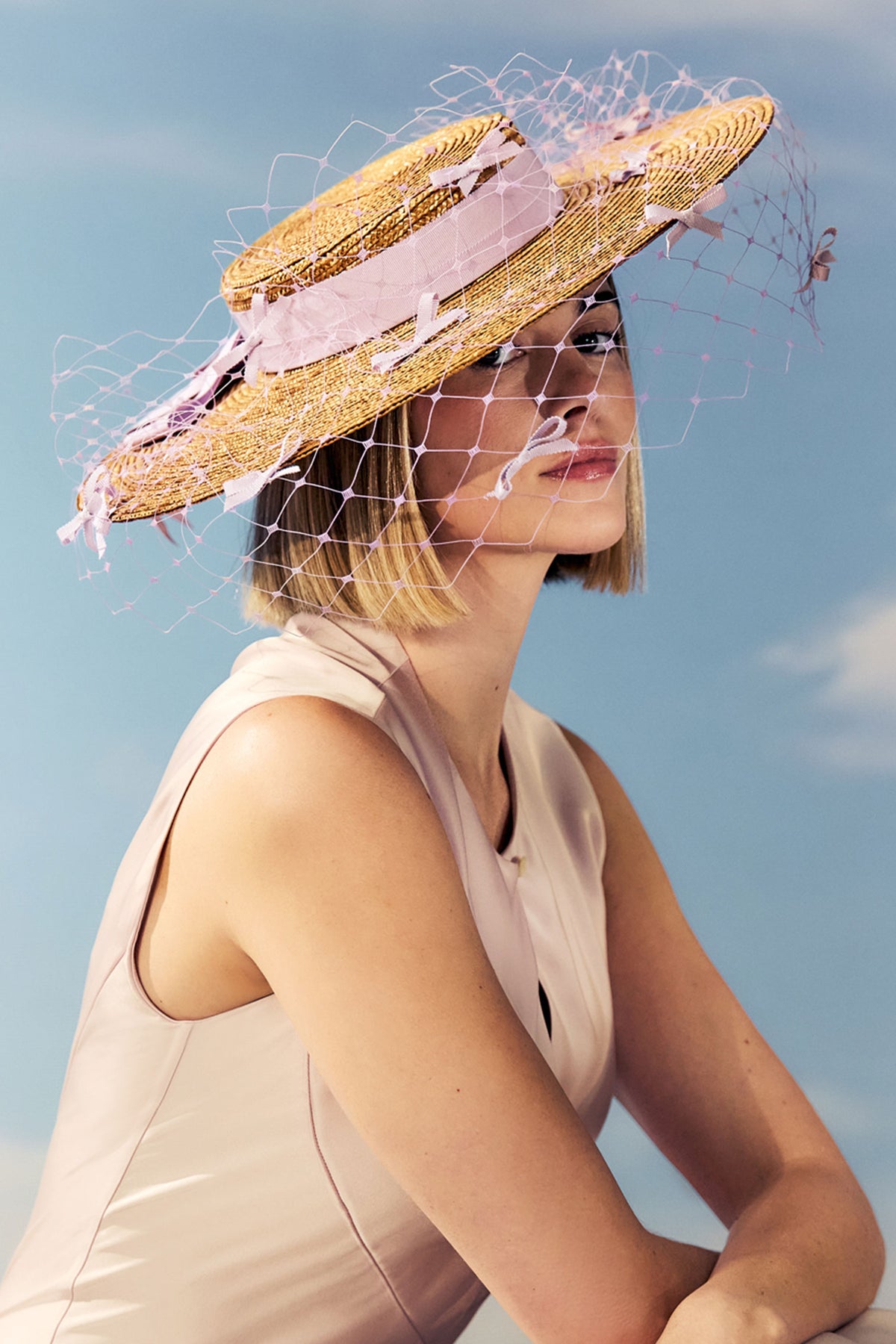 Golden pedal straw boater hat with a lilac cotton petersham ribbon and lilac veiling adorned with miniature bows.