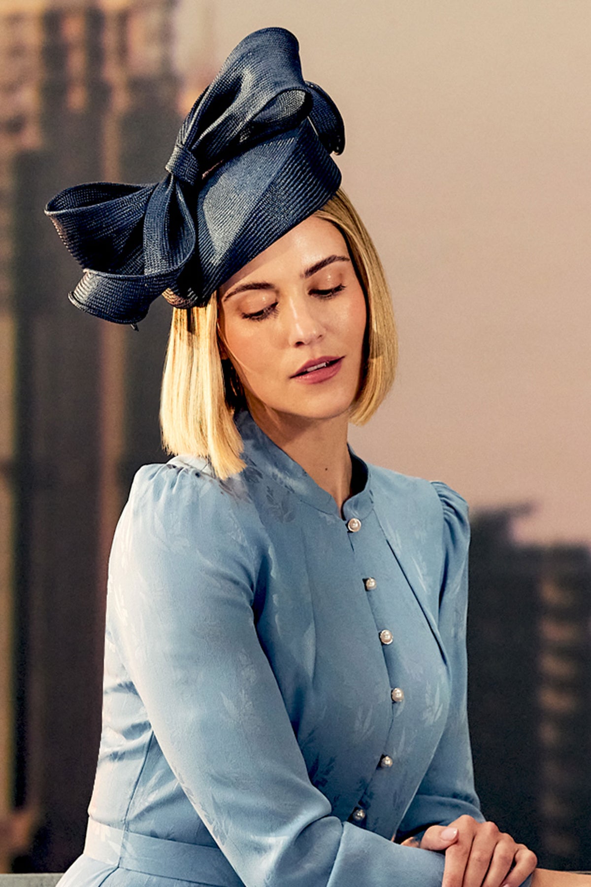 Women's navy parasisal straw pillbox hat with a hand sculpted bow.